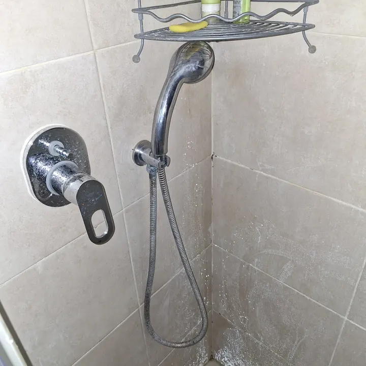 סוללת מקלחת מודרנית עם מקלחון יד על קיר אריחים בהיר